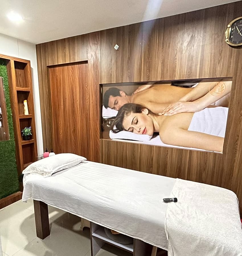 A massage room, with the bed made up against a wood-panelled wall